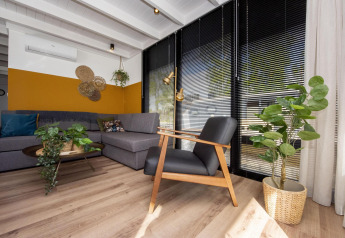 Salon moderne sur la péniche 'De Waterparel' avec canapé gris, stores noirs et plantes vertes à Friesland.