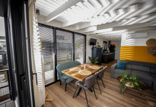 Sala moderna en la casa flotante 'De Waterparel' en Frisia con ventanas grandes y zona de comedor acogedora.