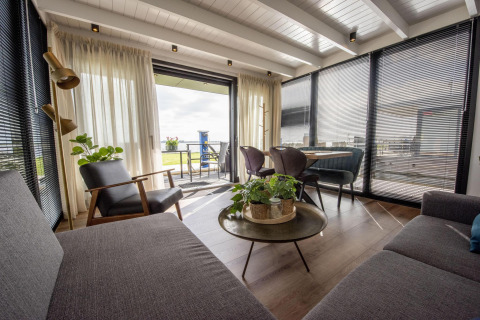 Modernes Wohnzimmer auf Hausboot 'De Waterparel' mit Panoramablick in Friesland, Niederlande.