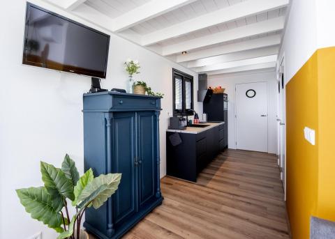 Sala moderna con cocina en la casa flotante 'De Waterparel', mueble azul y televisor en la pared.