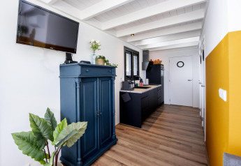 Sala moderna con cocina en la casa flotante 'De Waterparel', mueble azul y televisor en la pared.