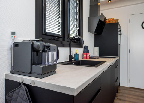 Cocina moderna de casa flotante con cafetera, fregadero y ventanas, en Houseboat 'De Waterparel' en Frisia, Países Bajos.