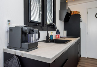 Cocina moderna de casa flotante con cafetera, fregadero y ventanas, en Houseboat 'De Waterparel' en Frisia, Países Bajos.