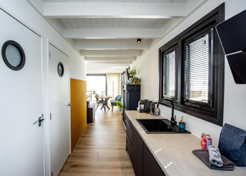 Interno moderno di una houseboat con cucina elegante, pavimento in legno e grandi finestre in Friesland.