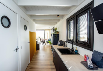 Modernes Hausboot-Interieur mit Küchenzeile, großen Fenstern und hellen Holzböden in Friesland.