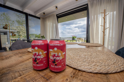 Dos latas de cerveza rubia sobre una mesa de madera en una casa flotante moderna en Friesland, Países Bajos.
