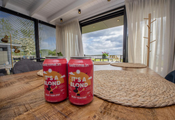 Dos latas de cerveza rubia sobre una mesa de madera en una casa flotante moderna en Friesland, Países Bajos.