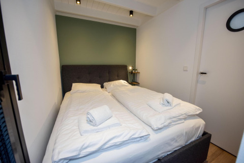 Dormitorio en la casa flotante 'De Waterparel' en Welcome In - Friesland, Países Bajos, con dos camas individuales.
