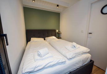 Dormitorio en la casa flotante 'De Waterparel' en Welcome In - Friesland, Países Bajos, con dos camas individuales.