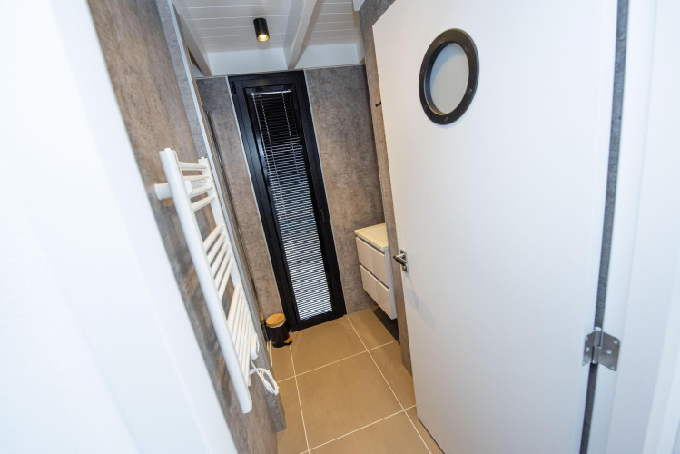 Modern bathroom on Houseboat 'De Waterparel' in Friesland, Netherlands, featuring a round door window and sink.