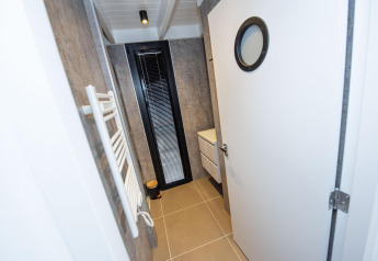 Modern bathroom on Houseboat 'De Waterparel' in Friesland, Netherlands, featuring a round door window and sink.