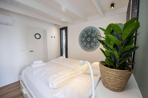 Dormitorio luminoso en la casa flotante 'De Waterparel' en Welcome In - Friesland, Países Bajos, decoración moderna.
