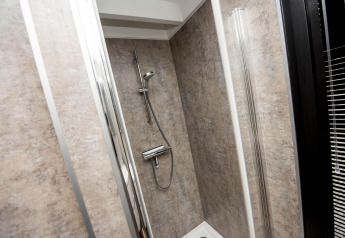 Cabina de ducha moderna con paneles beige en la casa flotante 'De Waterparel' en Welcome In - Friesland, Países Bajos.