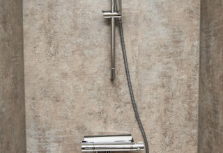 Ducha moderna con grifería cromada y manguera en el baño de la casa flotante 'De Waterparel' en Frisia.