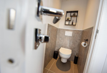 Baño moderno en la casa flotante De Waterparel con inodoro suspendido y estantería decorativa en Friesland.