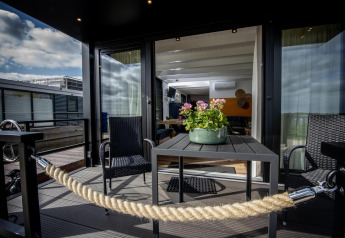 Terraza exterior de la casa flotante 'De Waterparel' en Welcome In - Friesland, Países Bajos, con mesa y sillas.