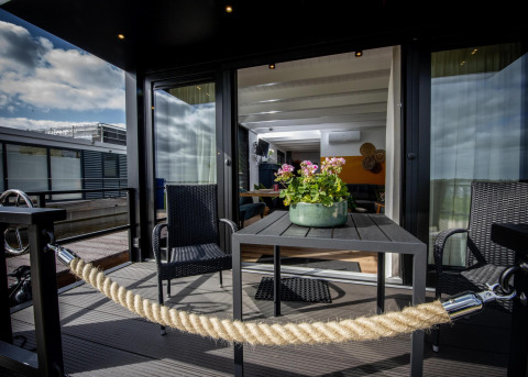 Terraza exterior de la casa flotante 'De Waterparel' en Welcome In - Friesland, Países Bajos, con mesa y sillas.