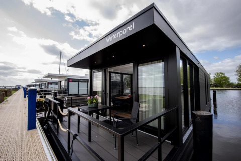 Moderne woonboot 'De Waterparel' aan de kade bij Welcome In - Friesland in Nederland.