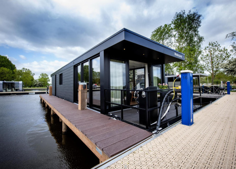 Casa flotante moderna 'De Waterparel' en Welcome In - Friesland, Países Bajos, atracada al muelle.