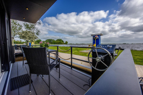 Terraza de la casa flotante 'De Waterparel' con vistas al agua en Welcome In - Friesland, Países Bajos.