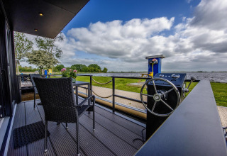 Terraza de la casa flotante 'De Waterparel' con vistas al agua en Welcome In - Friesland, Países Bajos.