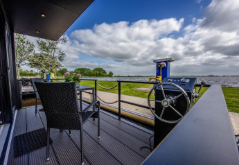 Terrasse du bateau-maison 'De Waterparel' avec vue sur l’eau à Welcome In - Friesland, Pays-Bas.