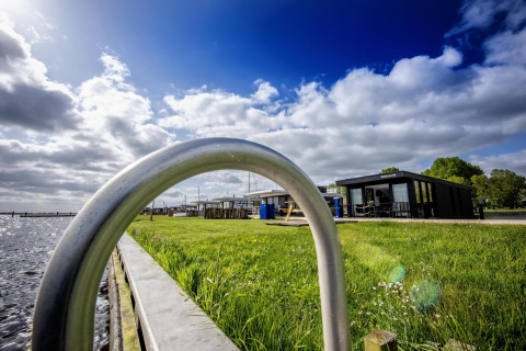 Casa flotante 'De Waterparel' en Welcome In - Friesland, Países Bajos, césped y vista al agua.
