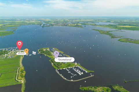Vista aérea de glamping junto al lago con barcos, marina, campos y marcadores de Beachclub y Starteiland.