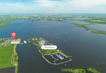 Vista aerea di glamping al lago con barche, marina, campi e indicatori per Beachclub e Starteiland.