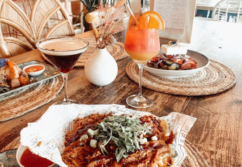 Leckeres Essen mit Cocktails, Nachos und Dips auf einem Holztisch in einer stilvollen Glamping-Unterkunft.