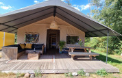 Hyggeligt safari-telt ved Zomerlicht i Holland med sofa, bord og terrasse omgivet af natur.