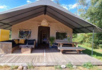 Tenda safari a Zomerlicht nei Paesi Bassi con veranda in legno, salotto e tavolo da picnic.