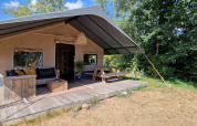 Tienda safari en Zomerlicht, Países Bajos, con terraza de madera, mesa de picnic y área de descanso.