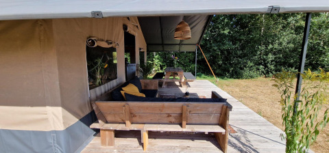 Area relax in legno davanti a una tenda safari a Zomerlicht, Paesi Bassi, immersa nella natura.