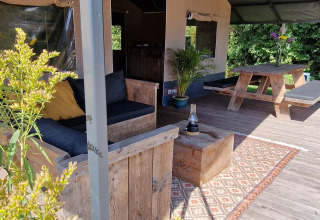 Tenda safari a Zomerlicht nei Paesi Bassi con mobili in legno, tappeto, lanterna e tavolo da picnic.