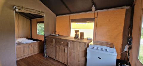 Interno di tenda safari presso Zomerlicht, Paesi Bassi, con angolo cottura, fornello, macchina da caffè e letto.