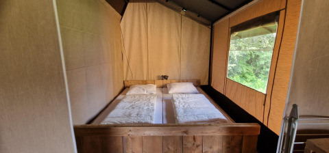 Zona de descanso en una tienda safari en Zomerlicht, Países Bajos, con vistas al bosque y cama doble.