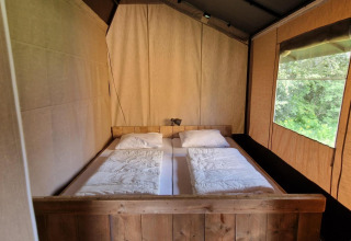 Zona notte con letto matrimoniale in tenda safari presso Zomerlicht nei Paesi Bassi, vista sulla natura.