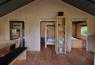 Interieur van een safaritent bij Zomerlicht, Nederland, met houten meubels en gezellige bedden.