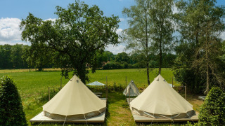 Due tende tipi su pedane di legno in un prato soleggiato al Holiday Park Mölke nei Paesi Bassi.