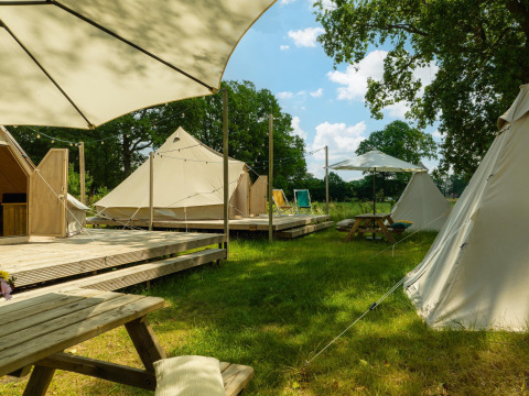 Glamping area with teepee tents, wooden decks, picnic tables, and umbrellas at Holiday Park Mölke, Netherlands.