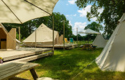 Glamping area with teepee tents, wooden decks, picnic tables, and umbrellas at Holiday Park Mölke, Netherlands.