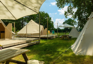 Aire de glamping avec tentes tipi, terrasses en bois, tables de pique-nique et parasols au Holiday Park Mölke, Pays-Bas.