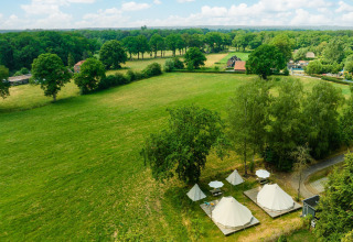 Vista aérea de tiendas tipi y sombrillas en un prado verde del Holiday Park Mölke en los Países Bajos.