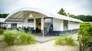Safari Tent Villa presso Holiday Park Duinhoeve nei Paesi Bassi, circondata da sabbia, verde e cielo nuvoloso.