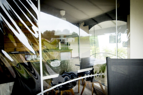 Binnenkijk door het raam van een safari Tent Villa in Holiday Park Duinhoeve, Nederland, met reflecties zichtbaar.