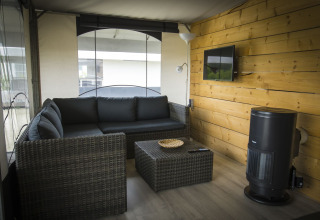 Moderne opholdsstue i en safaritelthytte på Holiday Park Duinhoeve, med komfortabel sofa og væghængt TV.