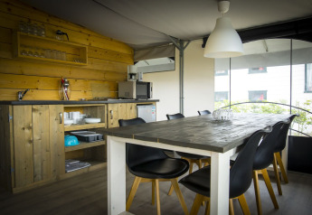 Cucina e zona pranzo moderne in una tenda safari a Holiday Park Duinhoeve, Paesi Bassi, con arredi in legno.