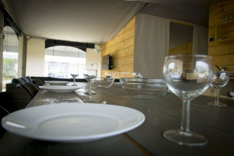 Set dining table with plates and glasses inside a safari tent villa at Holiday Park Duinhoeve, Netherlands.