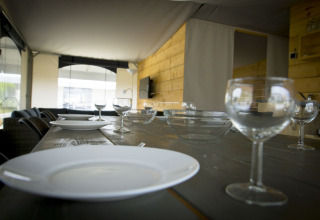 Set dining table with plates and glasses inside a safari tent villa at Holiday Park Duinhoeve, Netherlands.